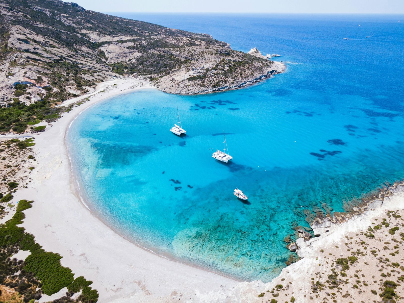 Blue sea beach and boats on the coast of Milos