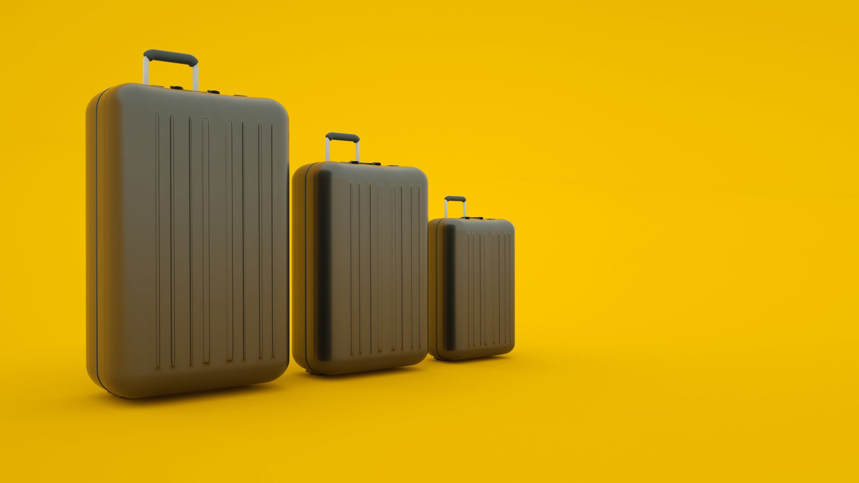 Three black suitcases of different sizes stand in a row with a yellow background