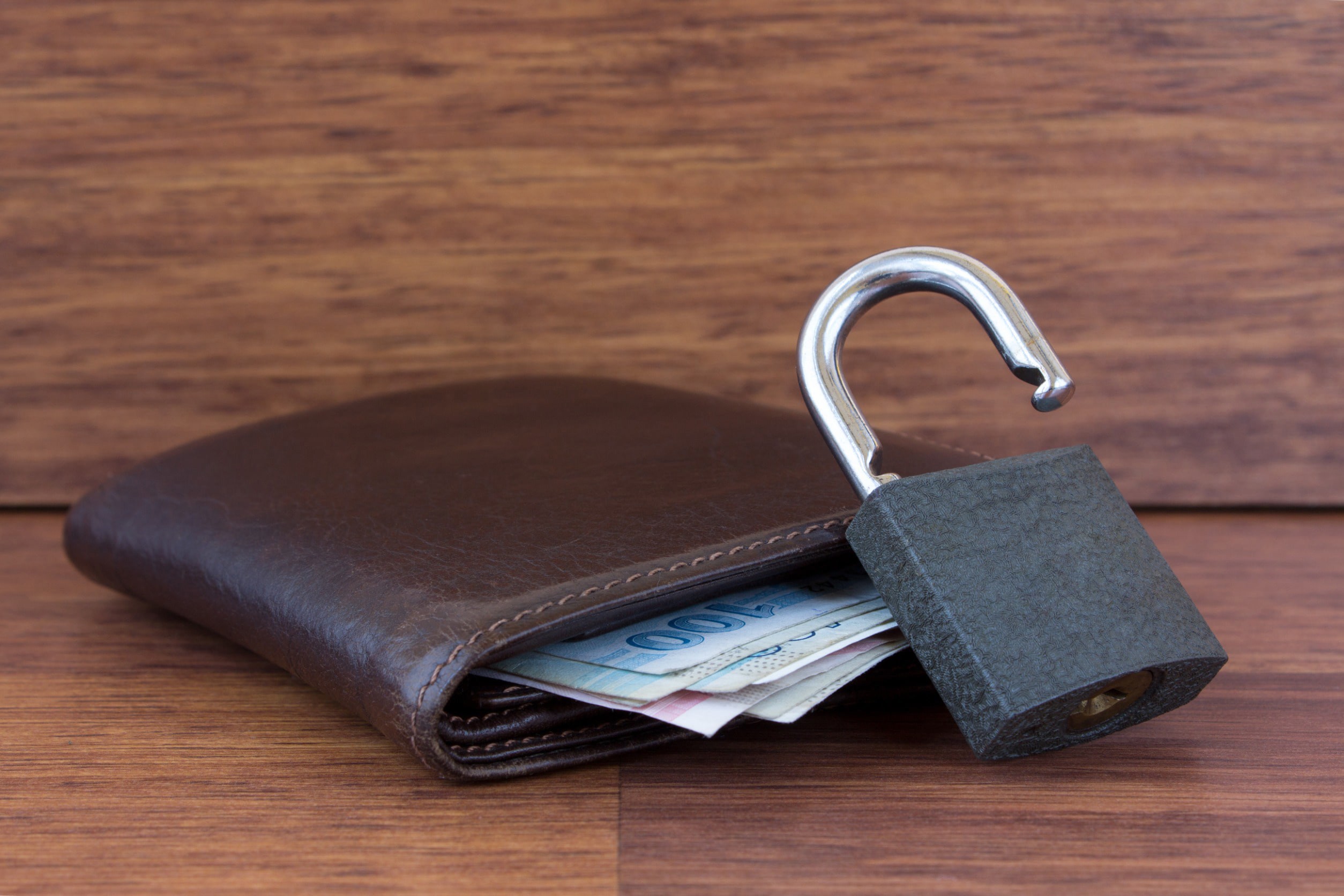 A wallet with a padlock next to it against a brown foundation