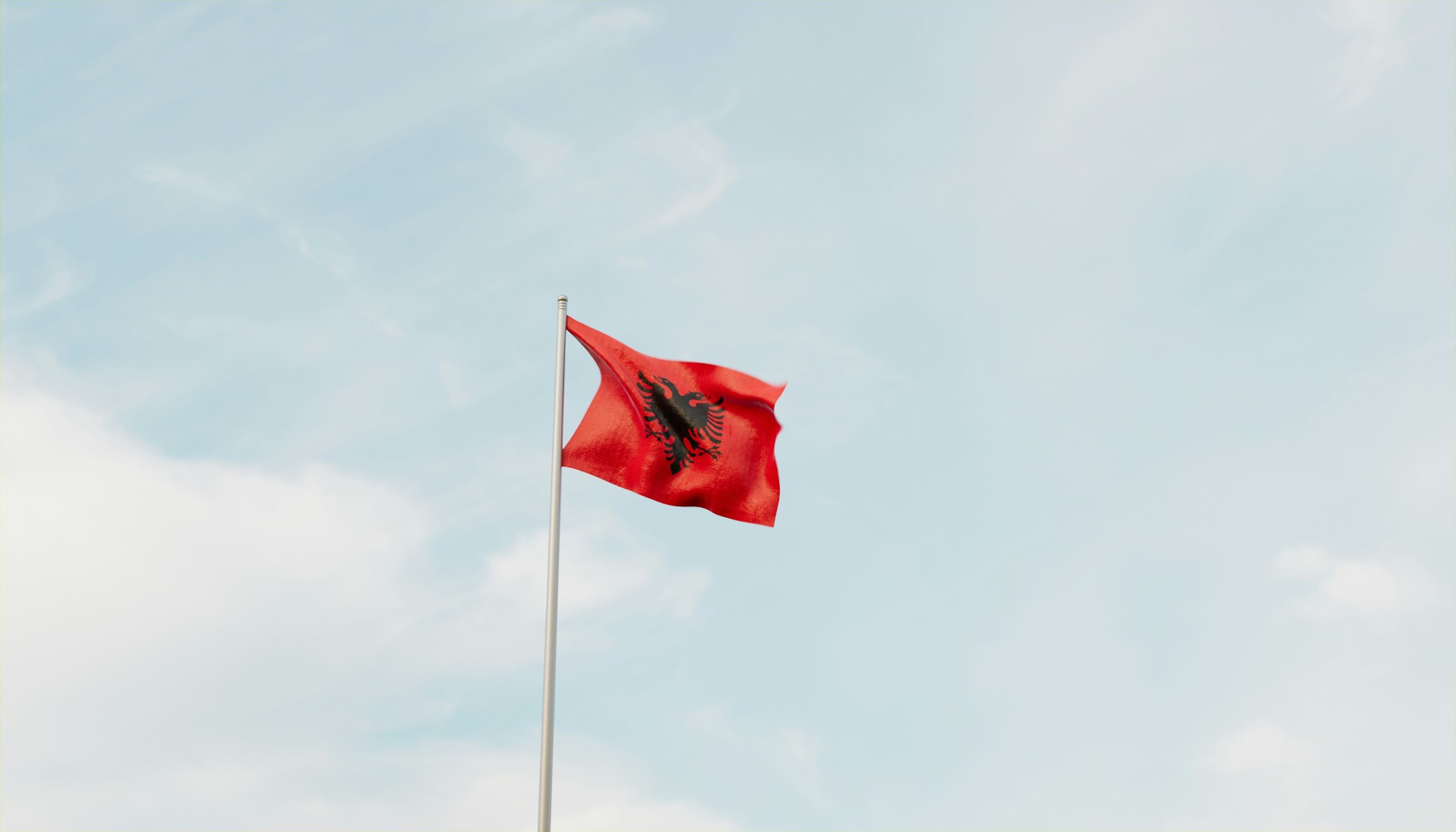 Albaniens flag vajer i luften mod en blå himmel