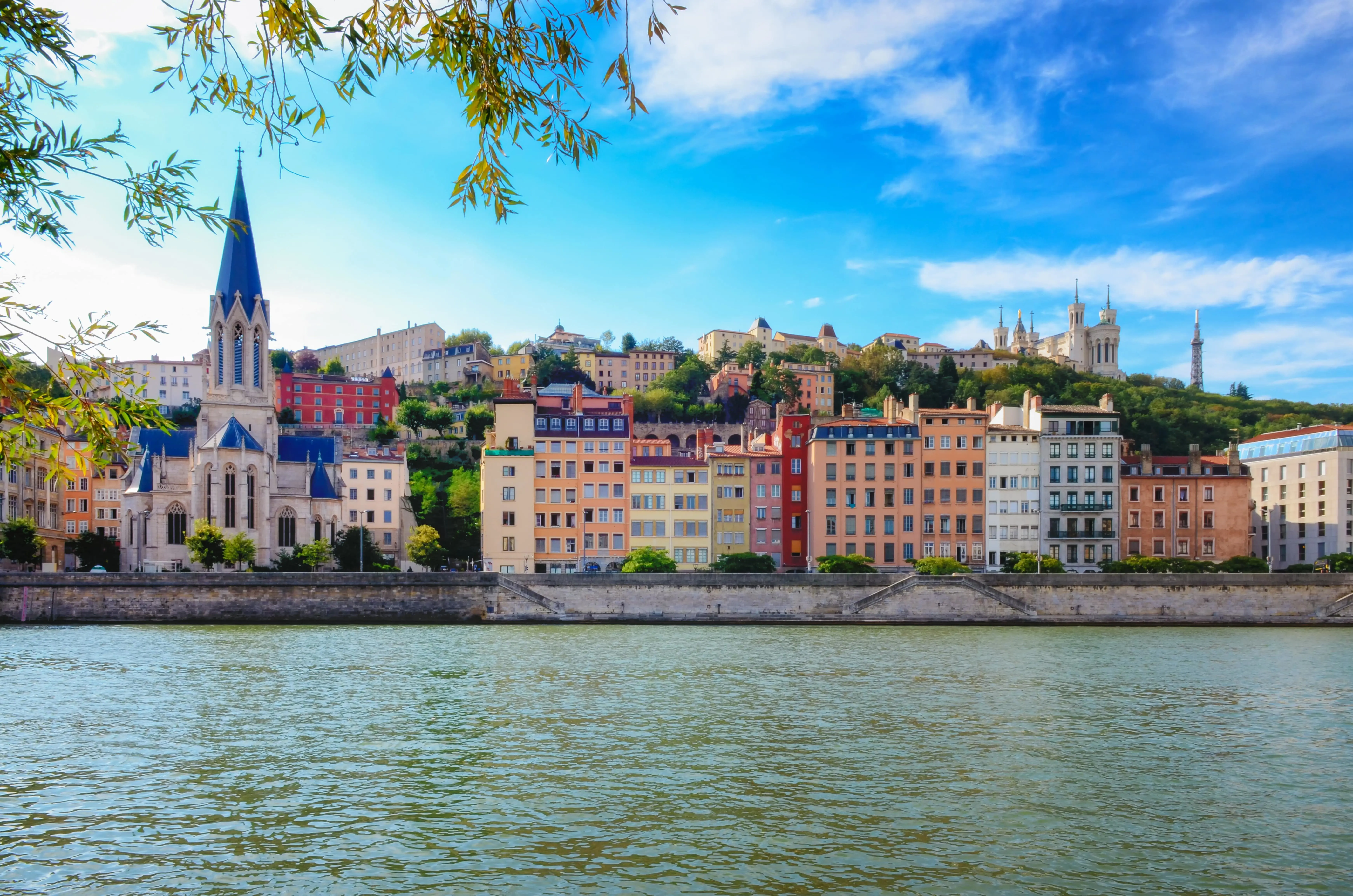 Travel to Lyon - View of water meeting Lyon city with colorful buildings and blue sky in the background