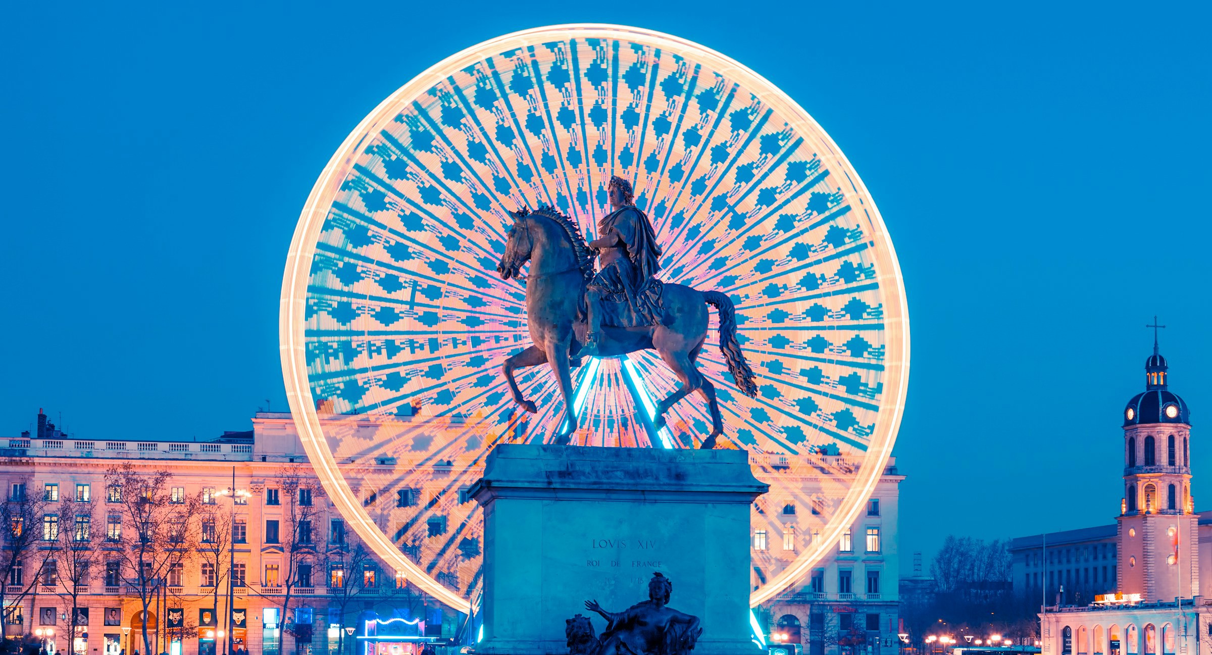 statue på en plads foran et parisisk hjul om aftenen i Lyon, Frankrig