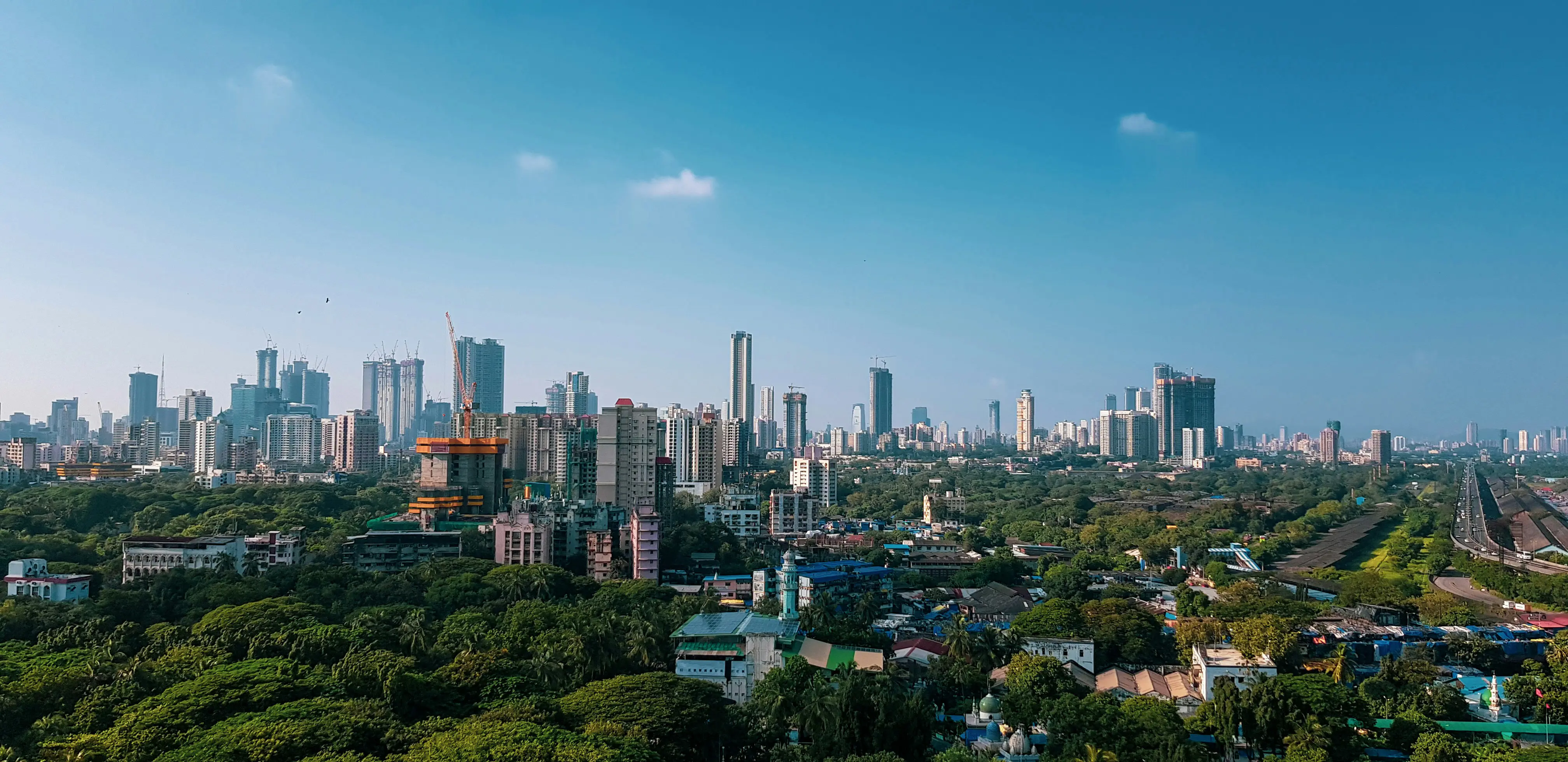 Rejs til Mumbai-Bombay - Panoramaudsigt over Mumbai med skyskrabere, grønne parkområder og en klar blå himmel.