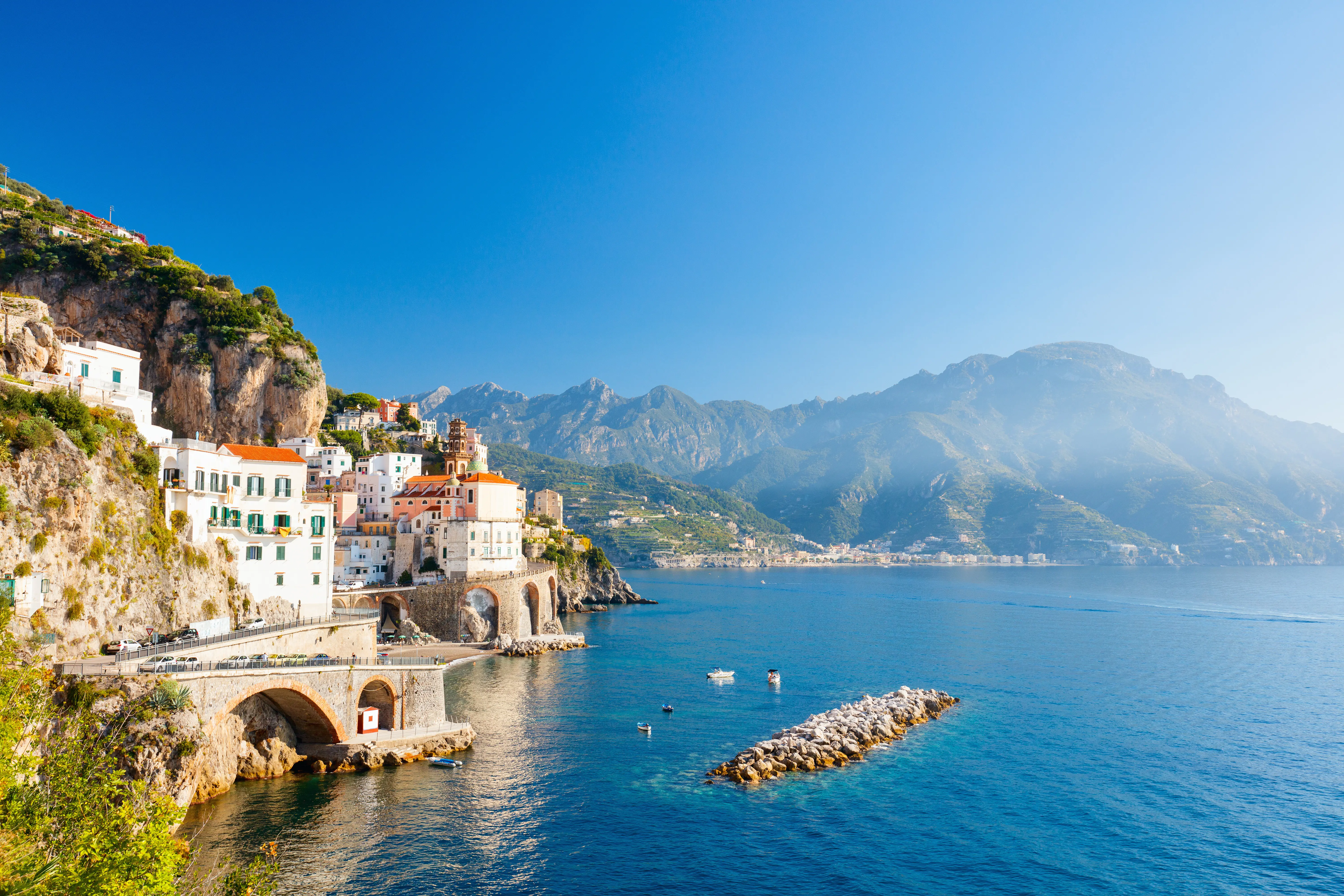 Buildings in a small harbor with blue sea and mountains in the background