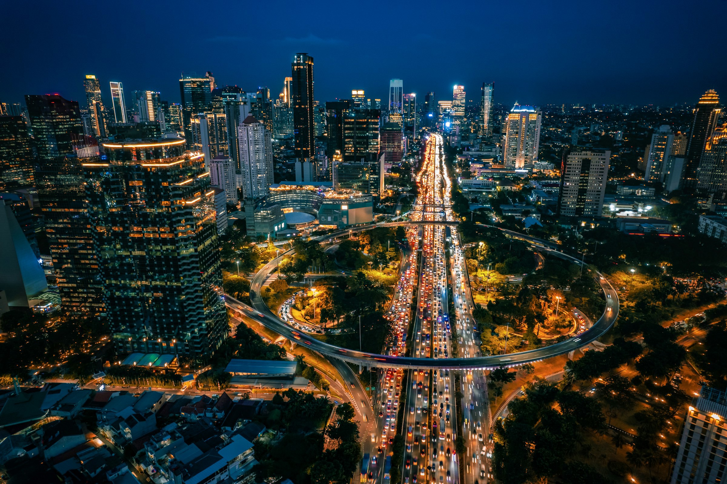 Udsigt over Jakarta by om natten med byen oplyst af lys, trafik og skyskrabere i baggrunden