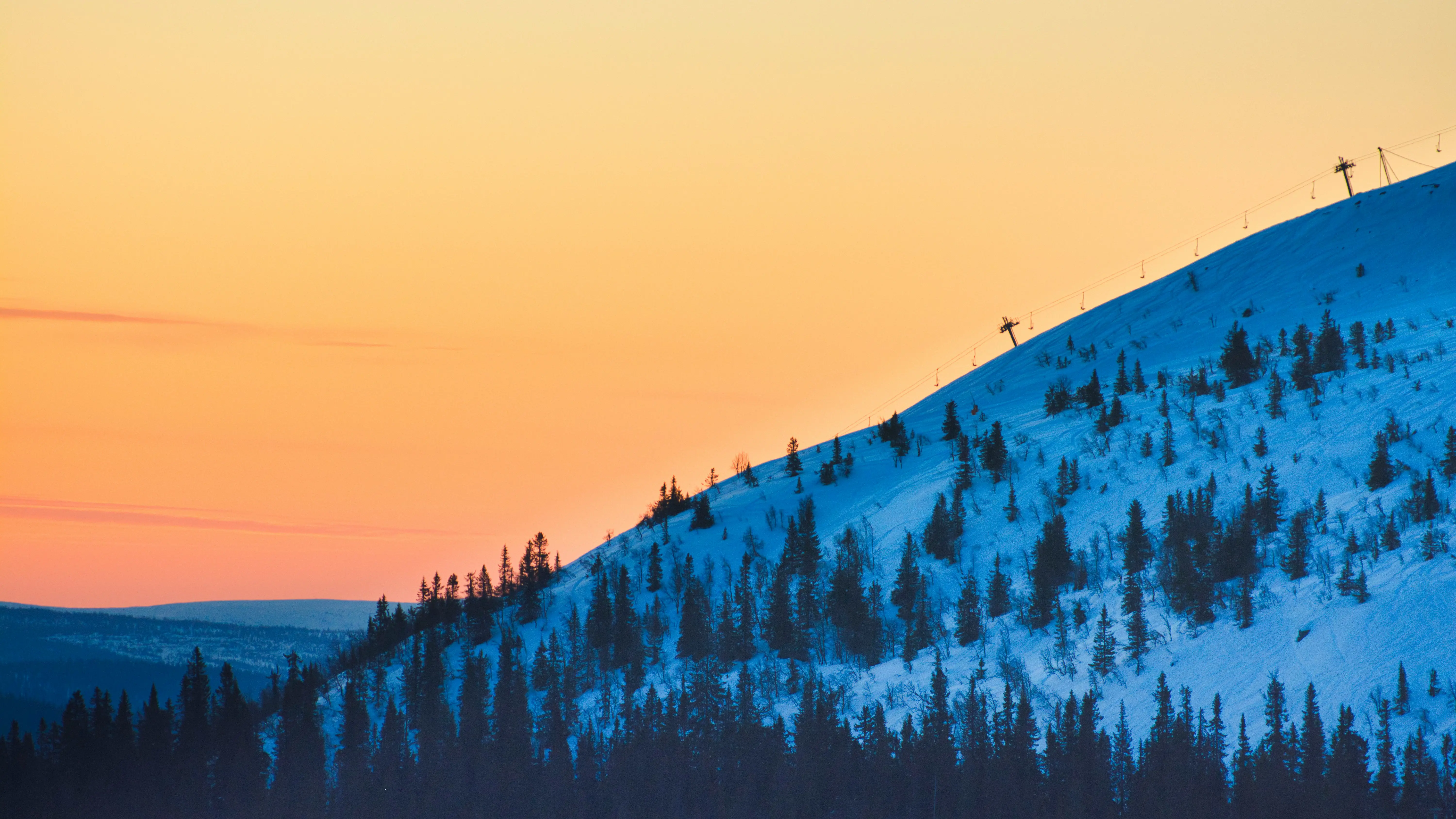 Travel to Trysil - Sunset over a snow-covered ski slope in Trysil with an orange sky in the background