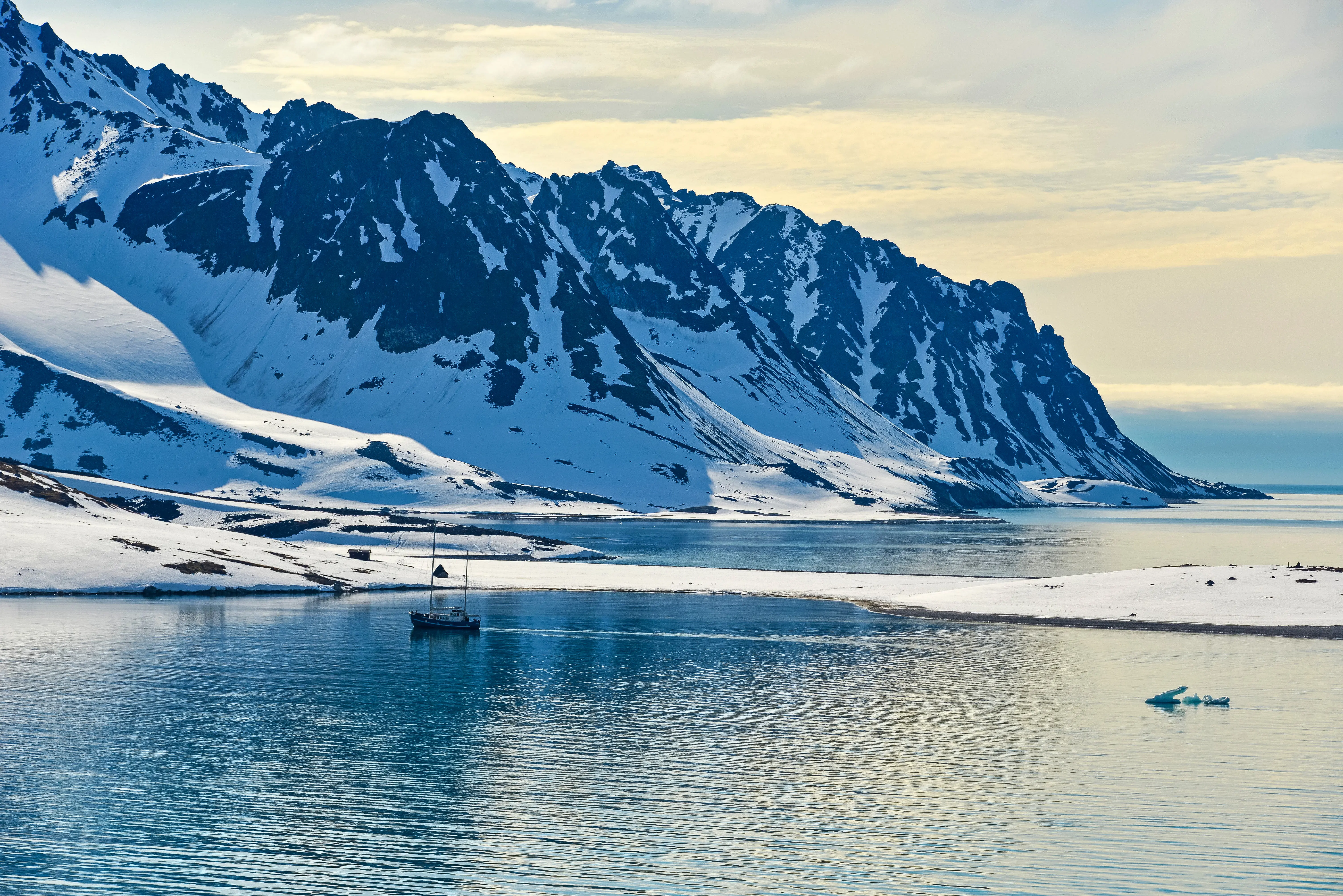 Snedækkede bjerge ned til isvand ved tidlig solnedgang på Svalbard