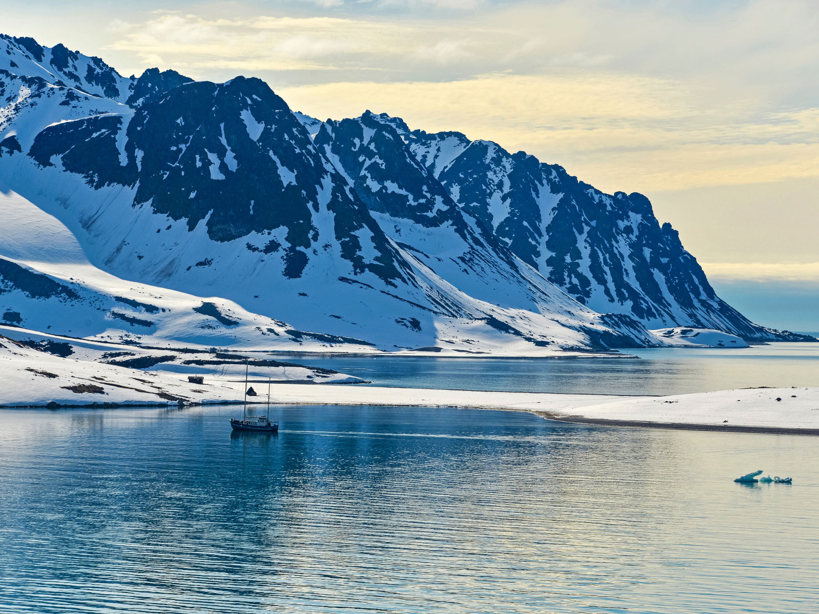 Snedækkede bjerge ned til isvand ved tidlig solnedgang på Svalbard