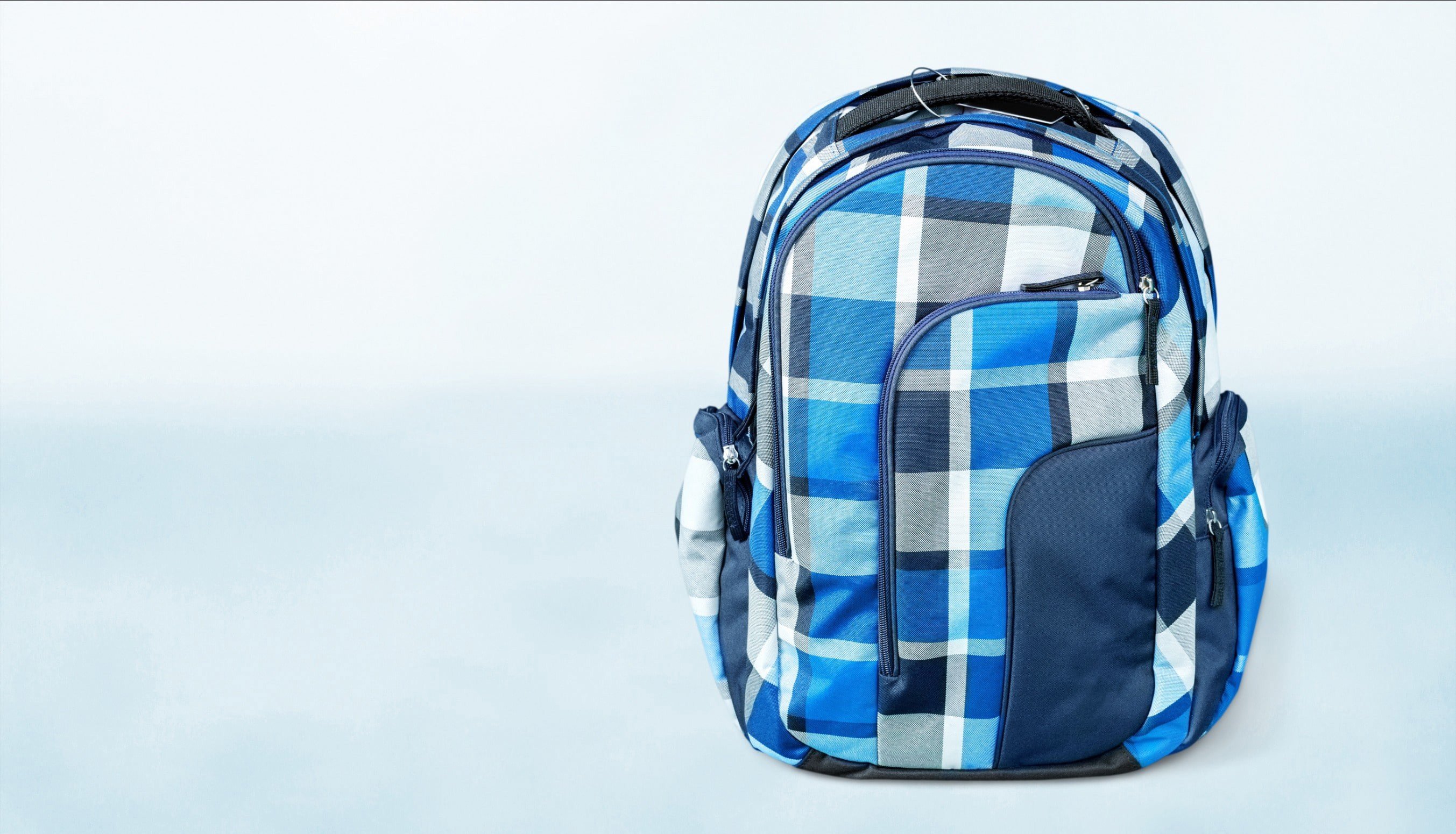 A blue backpack for kids with checkered patterns against a white background