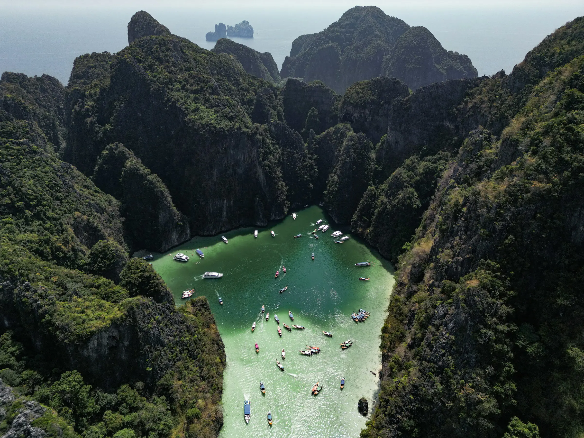 Fugleperspektiv af Pileh Lagoon på Phi Phi-øerne i Thailand med blåt hav omgivet af grønne bjerge