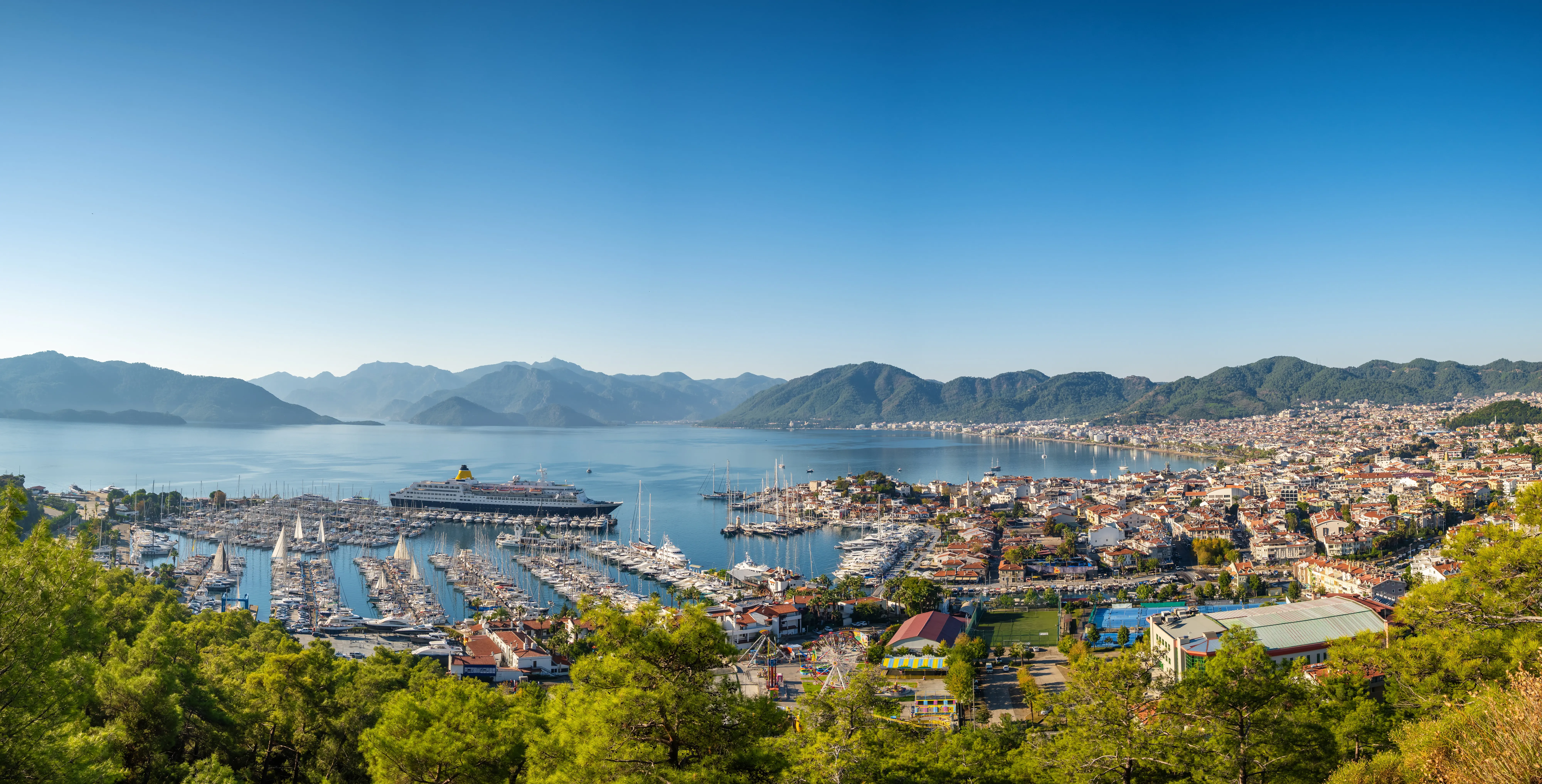 Travel to Marmaris - Panoramic view of Marmaris city with lush trees, buildings, the sea and beaches greeted by a blue sky